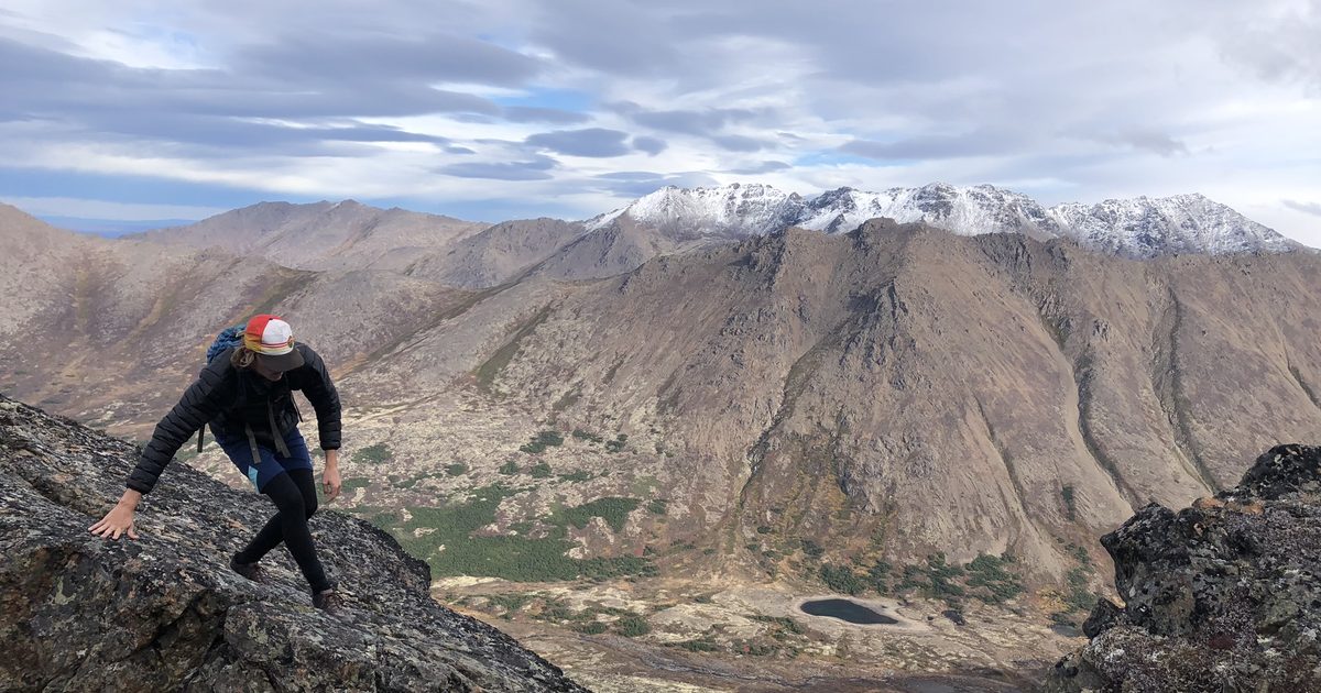 A runner scrambling up a mountain ridge in Alaska